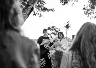 black and white photo of two inidviduals reading a script (with a mic) in front of a crowd