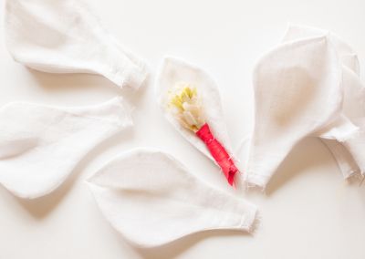progress shot of a fabric flower on a white background. In the photo are a handful of white petals and a red and yellow stamen